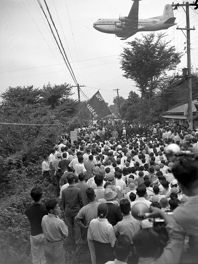 A U.S. Air Force plane flies over protestors in front of Tachikawa Airfield on September 13, 1955.