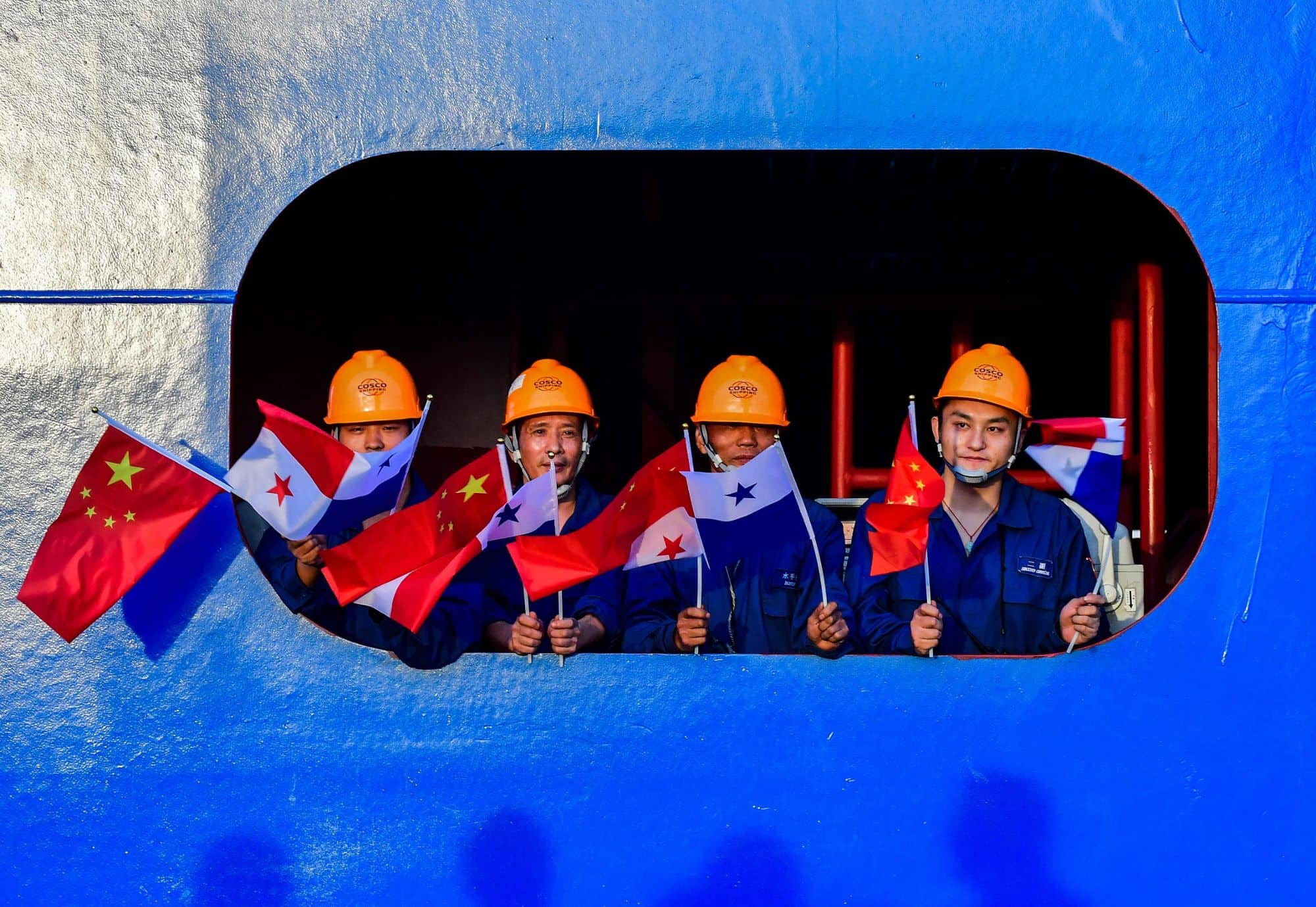 Crew members of a Chinese container ship wave Chinese and Panamanian flags during an official visit by Chinese President Xi Jinping to the country in December 2018.